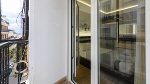 A modern hotel room with a glass door leading to a balcony. The room features a bed, a small table, and a sofa. - M Scsd14 Amplio Piso Exterior de 2 Dormitorios e (Madrid)