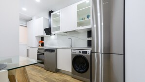 A modern kitchen with stainless steel appliances, white cabinetry, and a glass dining table. - M Scsd14 Amplio Piso Exterior de 2 Dormitorios e (Madrid)