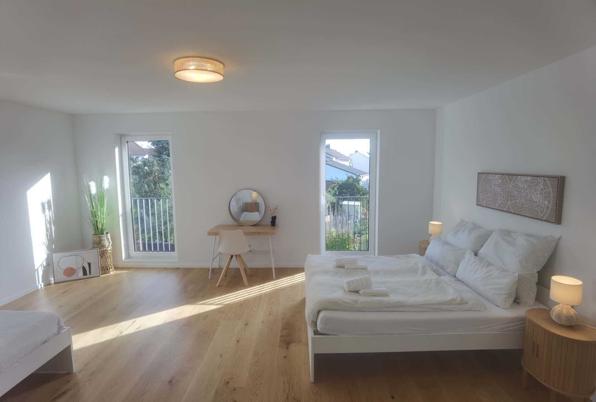 Een slaapkamer met een bed, een bureau en twee ramen.