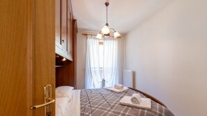 A hotel room with a bed, a wooden door, a window with curtains, and a ceiling light fixture. - The Space🏔 Beautiful Mountain House 5 Minutes from the Alleghe Slopes – Comfort & Nature in the Heart of the DolomitesExperience a unique stay in the Dolomites in a mountain house cared for in every detail, perfect for ski lovers in winter and hikin (Alleghe)