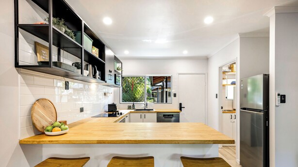 A modern kitchen with a wooden countertop, three bar stools, a stainless steel refrigerator, and a window with a view of greenery. - Family-Friendly Pool & Patio Retreat, Walk to Beach & Dining (Trinity Beach)