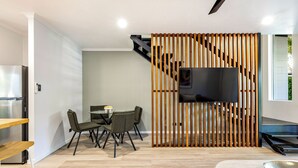 A modern kitchen with a built-in refrigerator, a dining area with a table and chairs, and a staircase with a wooden railing. - Family-Friendly Pool & Patio Retreat, Walk to Beach & Dining (Trinity Beach)