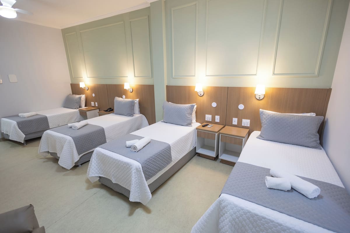Une chambre d’hôtel avec quatre lits simples, chacun étant équipé d’un oreiller et d’une serviette roulée.