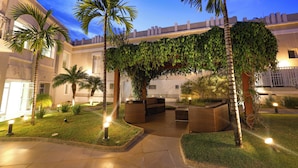 A courtyard with palm trees, outdoor seating, and a building facade.