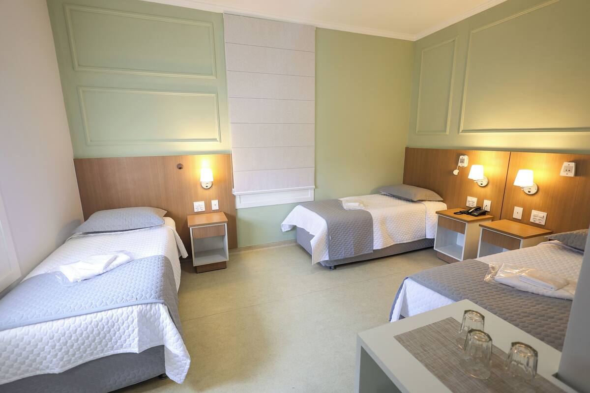 Une chambre d’hôtel avec deux lits simples, une petite table avec des verres et des lampes de chevet.