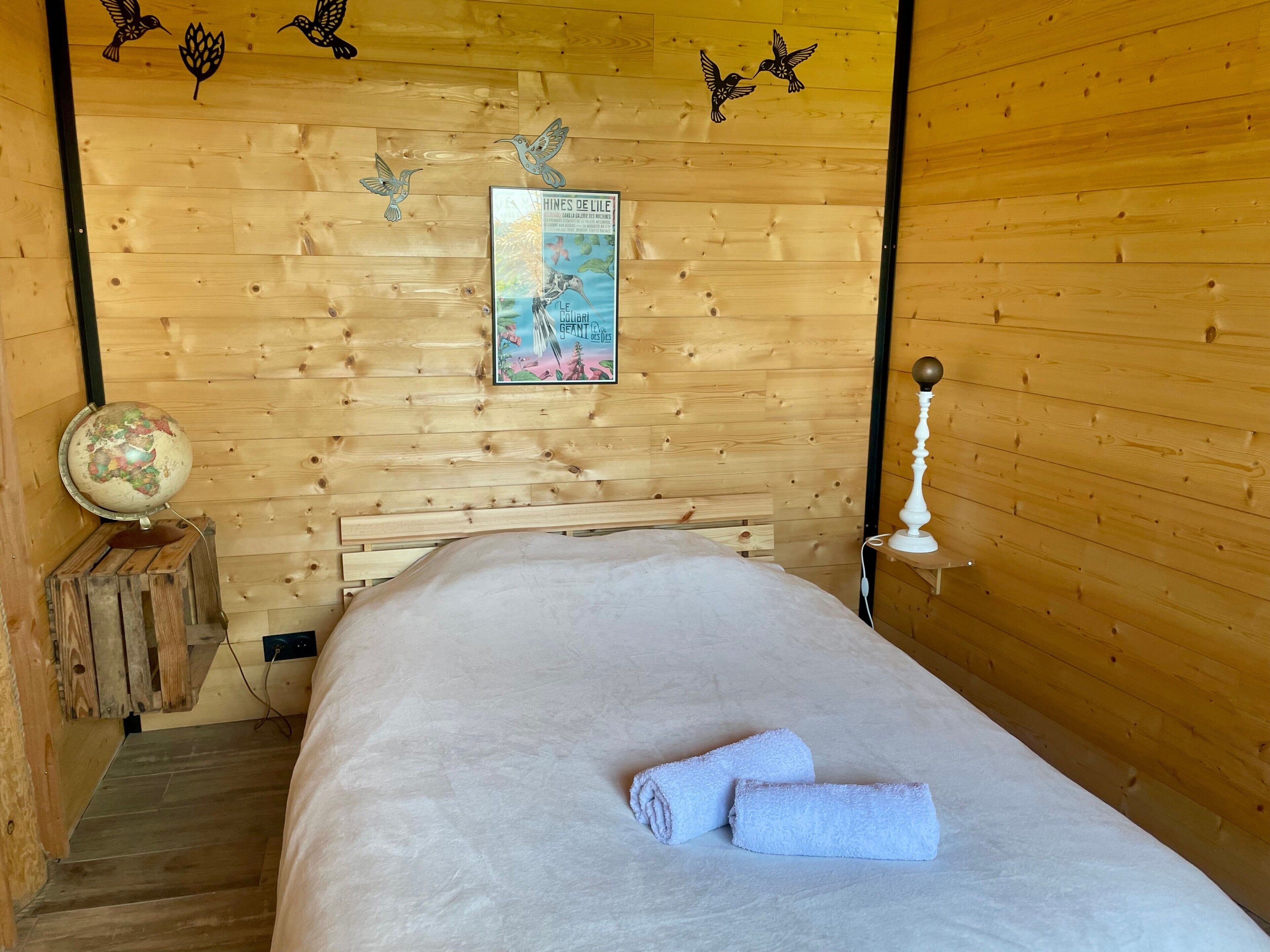 Una habitación de madera con una cama, un globo terráqueo y un cartel en la pared.
