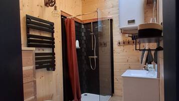 En lille træhytte med ovenlys, brusebad, toilet og håndvask.
