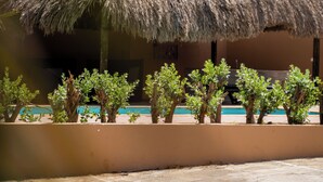 Eine reetgedeckte Hütte mit Pool und Palmen.