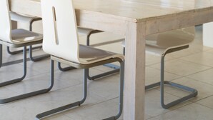Ein Essbereich mit Holztisch, weißen Stühlen und einer Pendelleuchte.