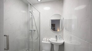 Ein modernes Badezimmer mit einer einteiligen Duschkabine, Toilette, Waschbecken und Spiegel.