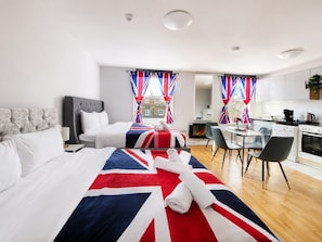 Una camera d'albergo con un letto grande, una zona notte separata, un'area pranzo e una cucina.