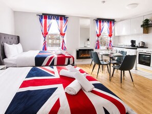 Una camera d'albergo con un letto, un tavolo da pranzo, sedie, una zona cucina e un camino.