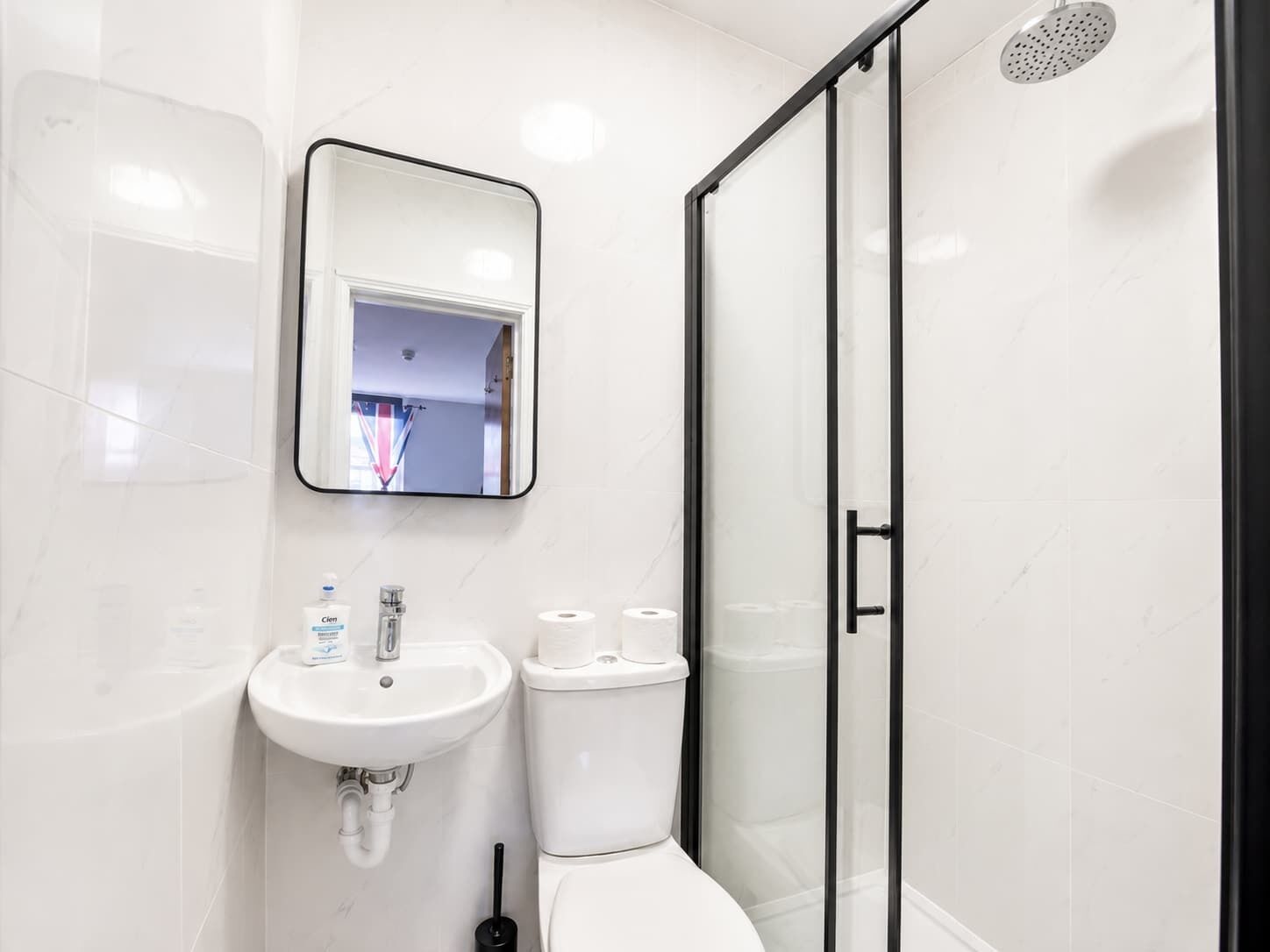 Een moderne badkamer met een witte wastafel, toilet en een douchecabine met glazen wanden.