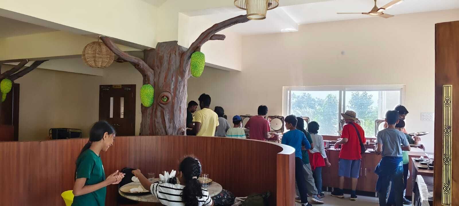 Un restaurante con una decoración temática de árboles, que incluye un tronco grande con cocos colgantes y una cesta de mimbre.
