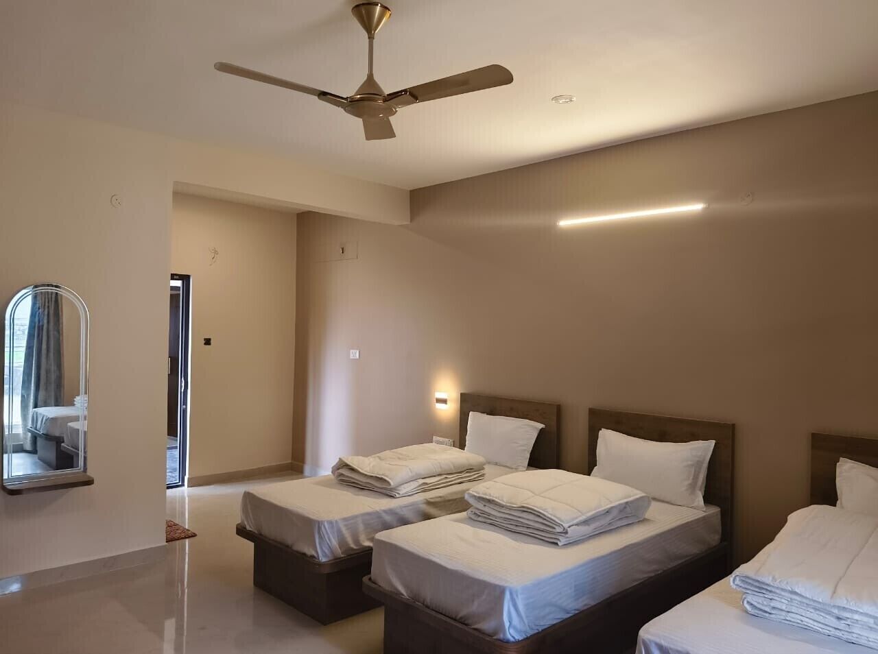Habitació d'hotel amb dos llits, un ventilador de sostre i un mirall gran.