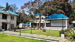A hotel with a modern design, featuring a courtyard with a lawn and potted plants. - MSB Silver Spring Resort Private Limited (Yelagiri)