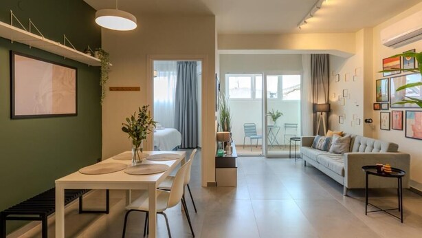 A modern living room with a dining area, a sofa, and a coffee table. - The Next Chapter Nilie Hospitality MGMT (Thessaloniki)