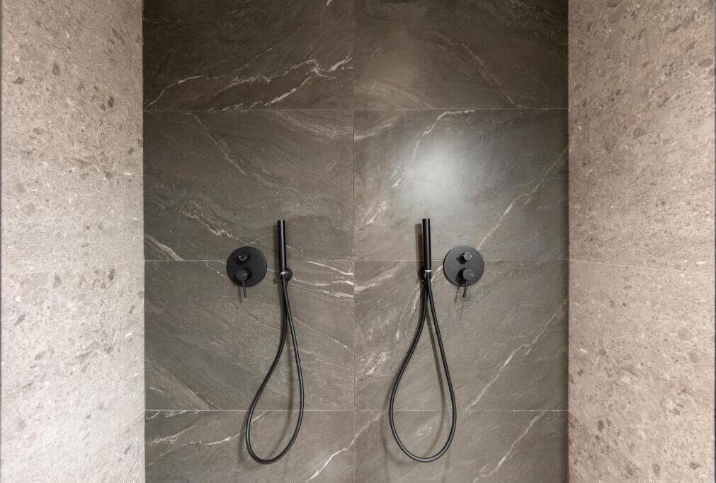 Un baño con dos cabezales de ducha empotrados en una pared con azulejos de mármol.
