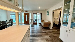 Un'ampia cucina con isola in legno, mobili bianchi e pavimento a spina di pesce.