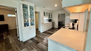 Una cucina moderna con mobili bianchi, pavimento in legno e forno a incasso.