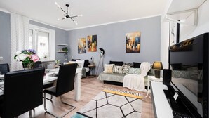 Un salon moderne comprenant un coin repas, un ensemble de canapés et un téléviseur.