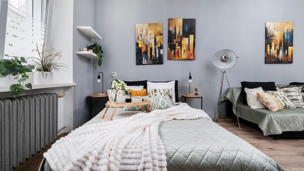 Une chambre à coucher moderne avec un lit, des tables de chevet, une lampe sur pied et des tableaux abstraits accrochés au mur.
