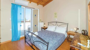 Ein Schlafzimmer mit einem Bett, einem Nachttisch, einer Holzbalkendecke und einem Fenster mit Vorhängen.