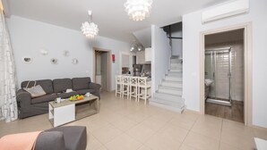 Een moderne woonkamer met een grijze bank, een bijzettafeltje met fruit en een trap die naar een badkamer leidt.