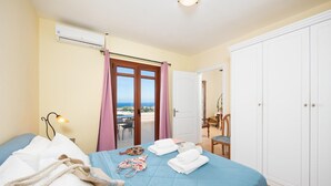 A hotel room with a bed, a balcony with a view, a wardrobe, and an air conditioning unit. - Villa Ikaros in Plaka (Apokoronas)