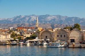 A coastal town with historic stone buildings, a prominent minaret, and boats docked in the harbor. - Villa Ikaros in Plaka (Apokoronas)