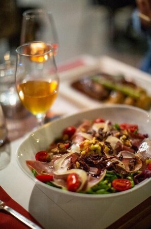 A dining table with a plate of food, a glass of wine, and a candle. - Villa Ikaros in Plaka (Apokoronas)