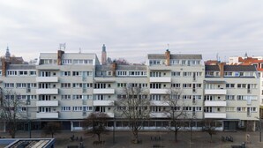 Un edificio residencial de varios pisos con fachada uniforme, balcones y techo plano.