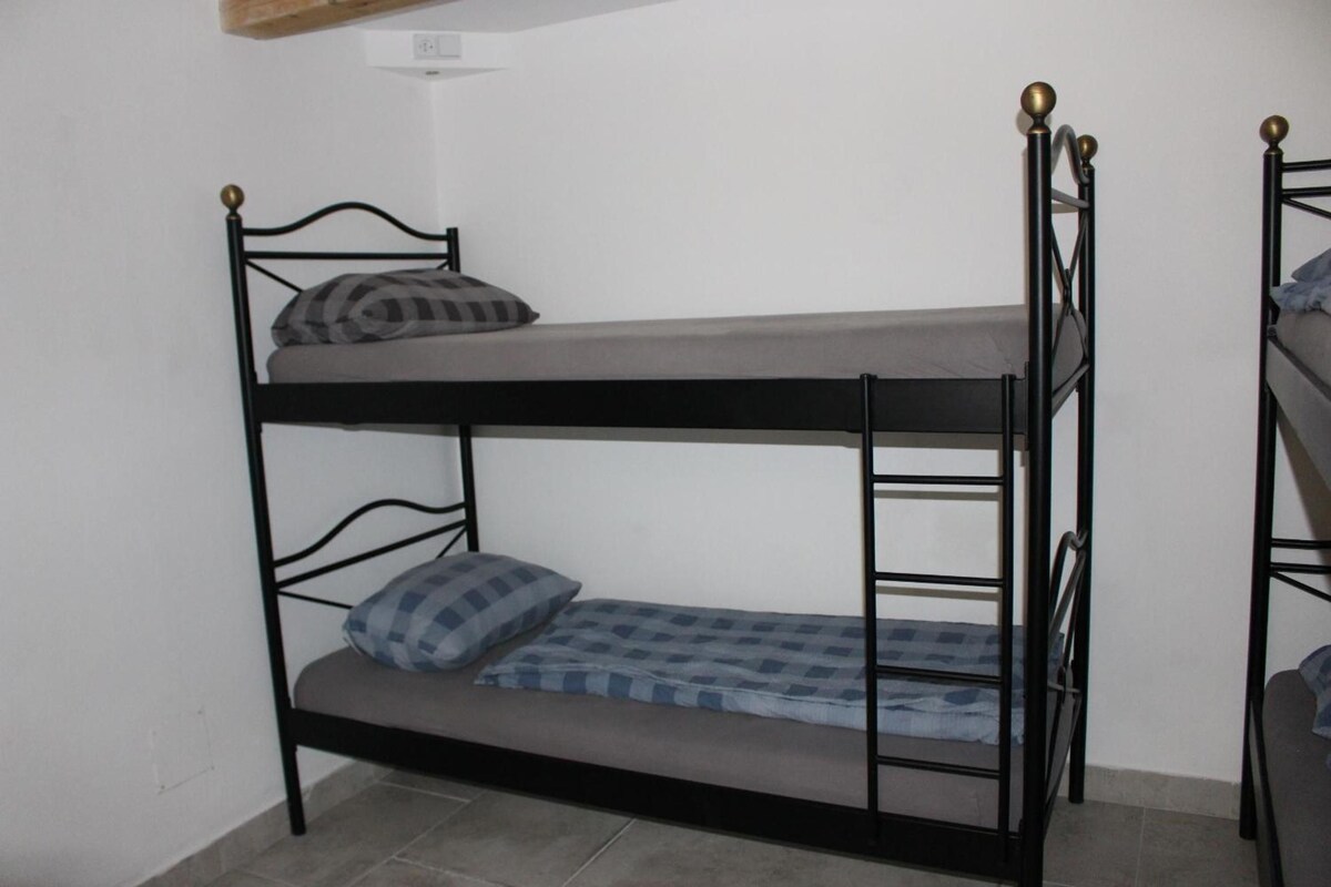 Ein Stockbett mit einer Matratze, Kissen und einer Leiter, sowie eine Wandsteckdose.