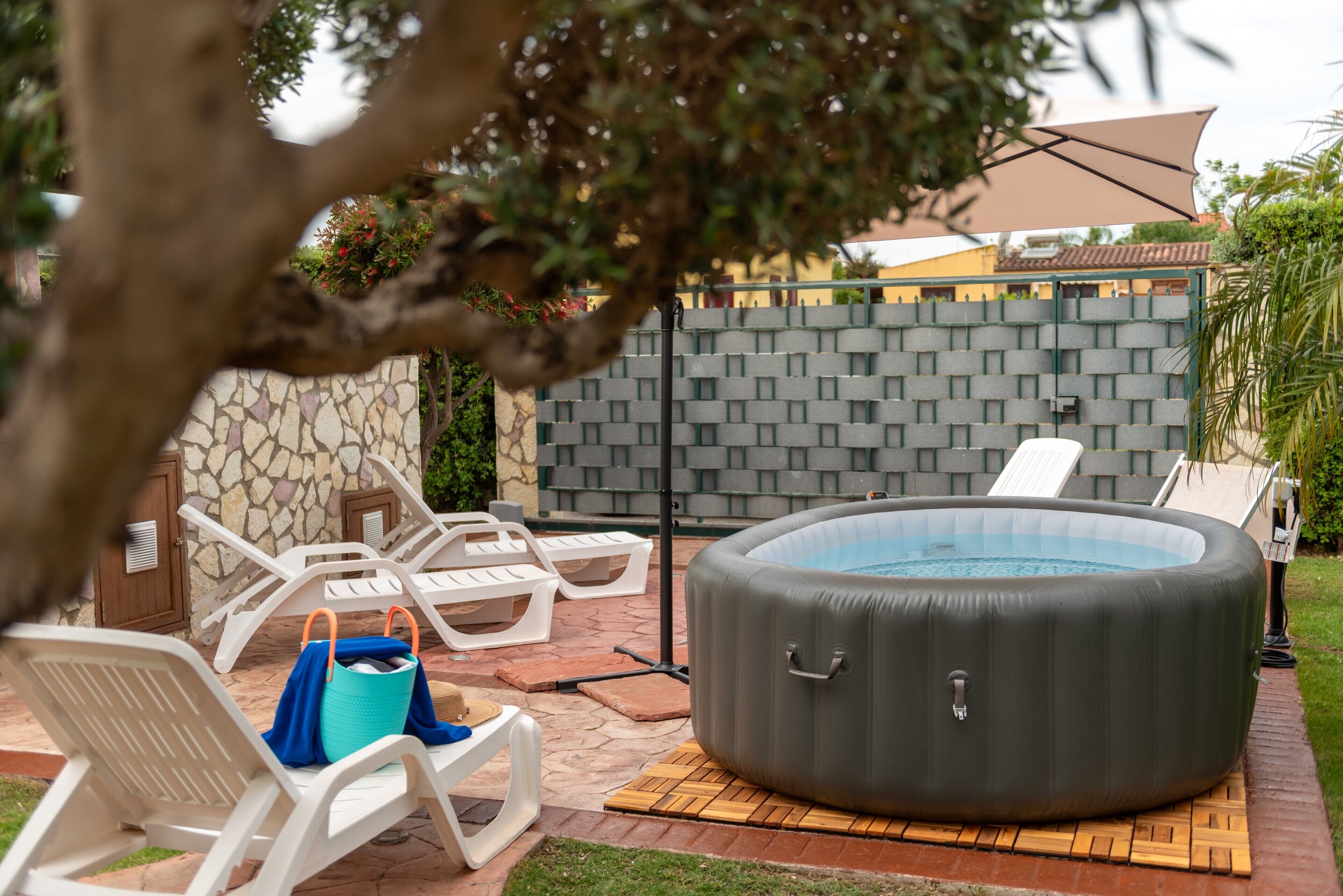 Ein Außenbereich mit Whirlpool, Liegestühlen, einer Steinwand und einer gefliesten Terrasse.