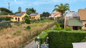 A residential area with houses, a road, and a green hedge. - Villa Tiffany with Private Terrace, Wi-Fi, Air Conditioning, and Garden View (Campofelice di Roccella)