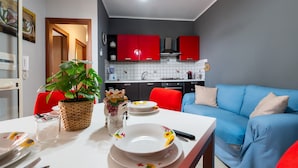 A compact living space with a dining area, kitchenette, and a blue sofa. - Villa Tiffany with Private Terrace, Wi-Fi, Air Conditioning, and Garden View (Campofelice di Roccella)