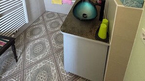 Un baño con bañera, ducha, lavabo con espejo y suelo estampado.