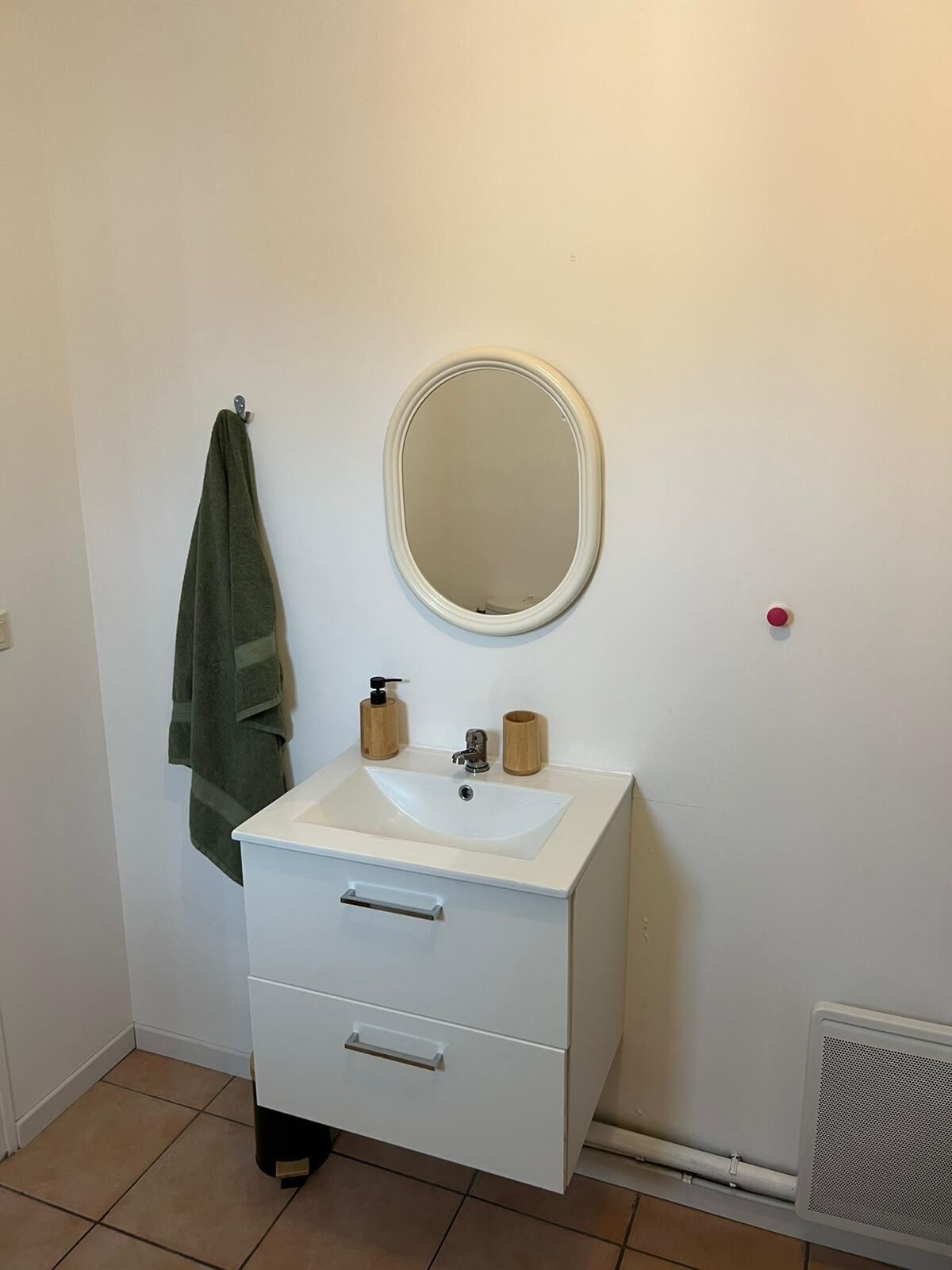 Une salle de bain avec un lavabo blanc, un miroir et une serviette accrochée au mur.