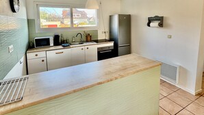 Une cuisine compacte dotée d’un grand îlot central, d’un four à micro-ondes, d’un évier et d’un réfrigérateur.