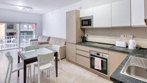 A modern kitchen with a dining area, a microwave, an oven, and a sink. - Live Where Malta Comes Alive, 2BR in Paceville! (St. Julian`s)