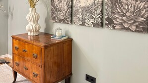 A room with a wooden dresser, a vase with dried plants, and a large botanical wall art piece. - Apartment "Fewo Sand 10 – Large" with Shared Terrace, Garden & Wi-Fi (Bamberg)