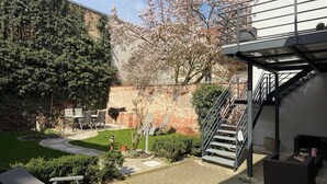 A patio area with outdoor furniture, a grill, a staircase, and a garden with a tree. - Apartment "Fewo Sand 10 – Large" with Shared Terrace, Garden & Wi-Fi (Bamberg)
