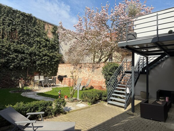 A patio area with outdoor furniture, a grill, a staircase, and a garden with a tree. - Apartment "Fewo Sand 10 – Large" with Shared Terrace, Garden & Wi-Fi (Bamberg)