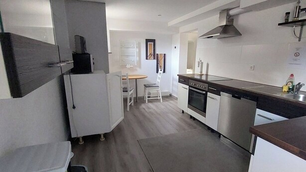 Uma cozinha moderna com armários brancos, forno de aço inoxidável e bancada de madeira.