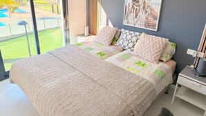 Quarto com cama grande, vista para uma piscina e um quadro na parede.