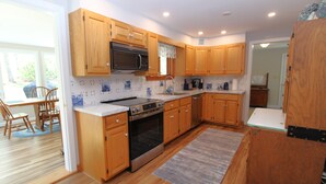 A kitchen with wooden cabinets, a stove, a microwave, and a sink. - Private Orleans Getaway Near Bakers Pond & Beaches (2422) (Orleans)