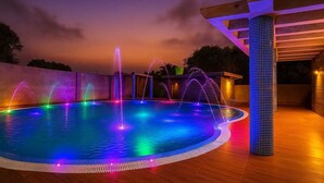 A swimming pool with multiple water jets and colorful lighting at night. - JYOTI RESORT JOYPUR (Bishnupur)
