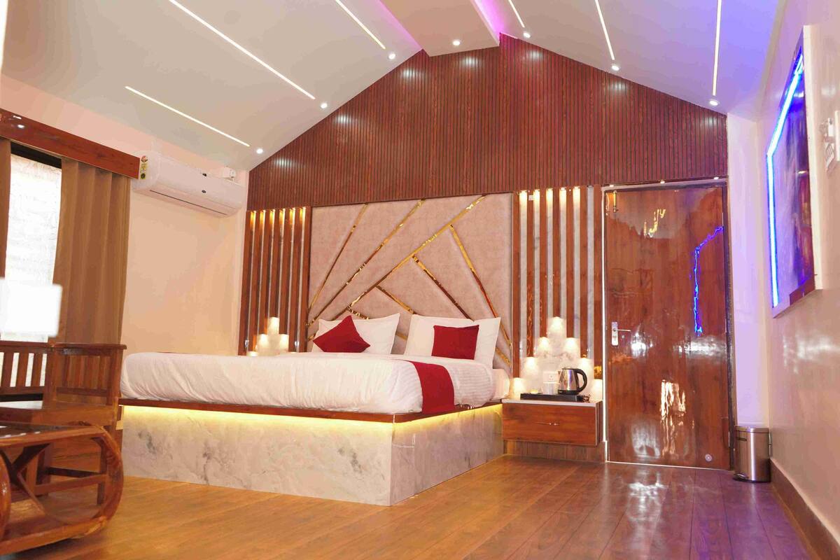 Un dormitorio moderno con una cama grande, paneles de madera, una mesita de noche y una pequeña mesa.