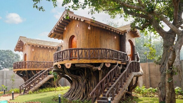 A treehouse with a wooden exterior, built into a large tree trunk, featuring a balcony and stairs. - JYOTI RESORT JOYPUR (Bishnupur)