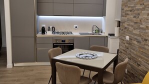 A modern kitchen with grey cabinets, a dining table with chairs, and a yellow sofa. - Delightful apartment recently renovated, central area well connected (Roma)